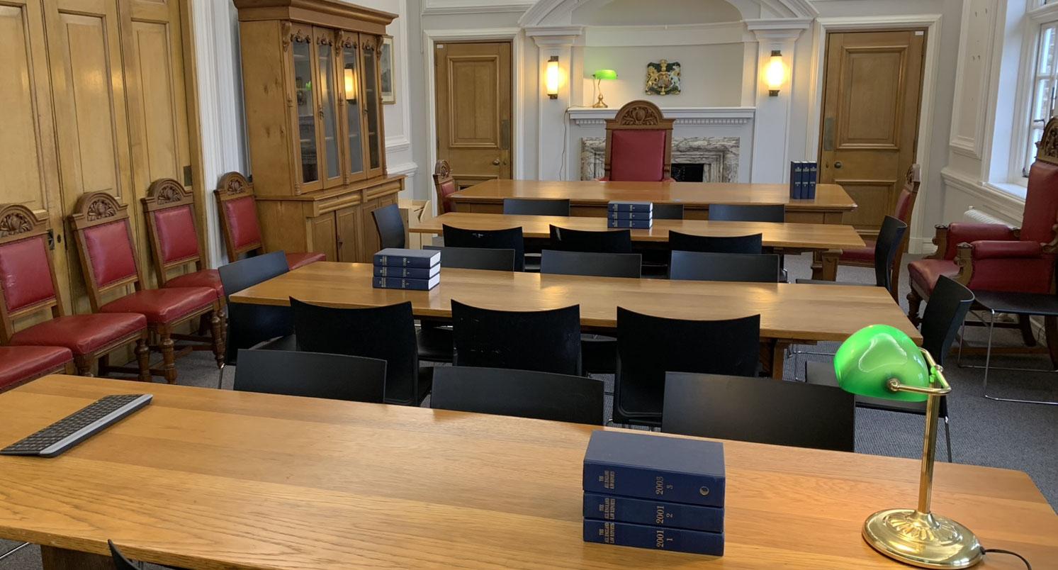The Council Chamber in Deptford Town Hall Building, featuring wood panelled walls, grand red and wooden chairs, and wooden tables