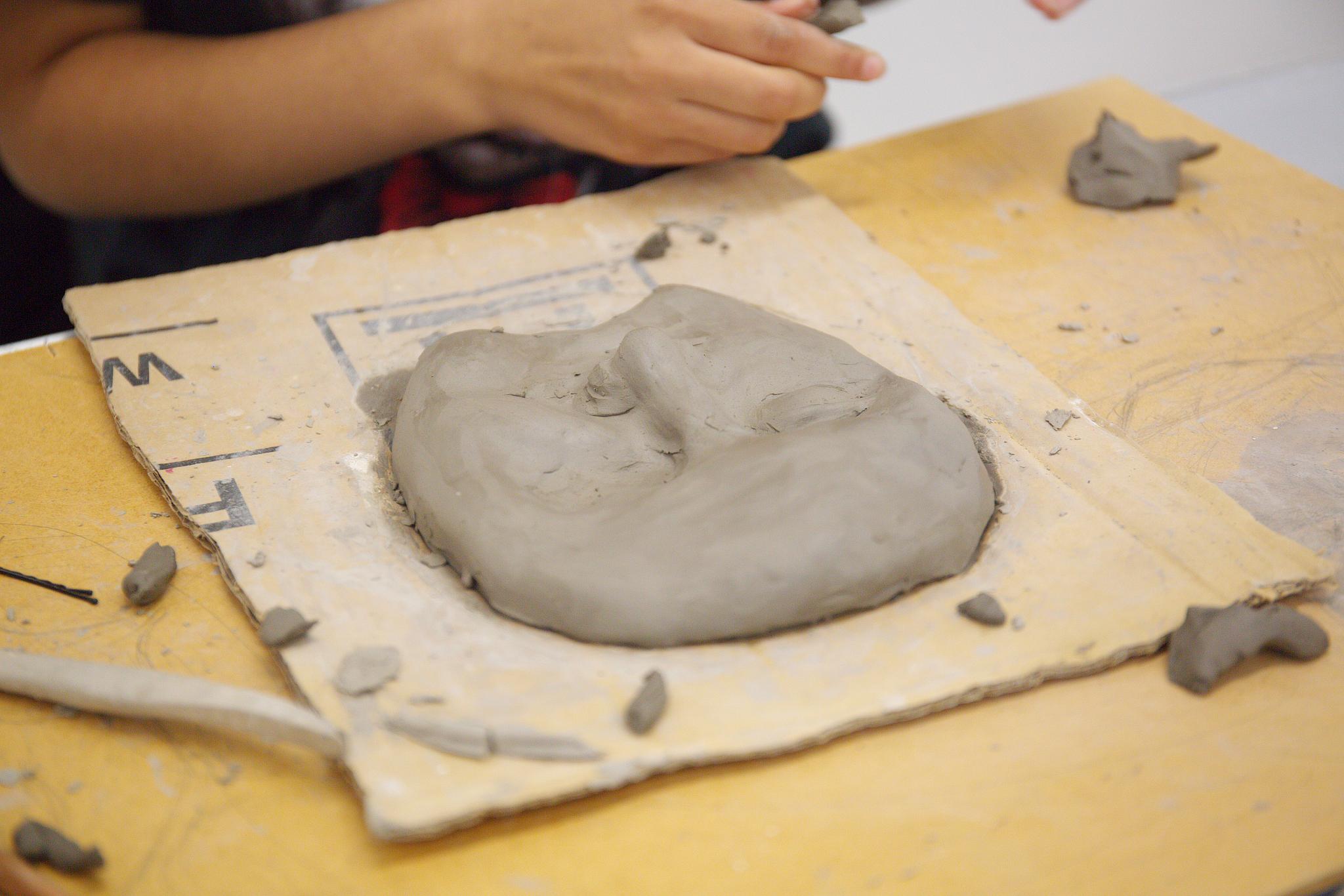 Clay face, on board 